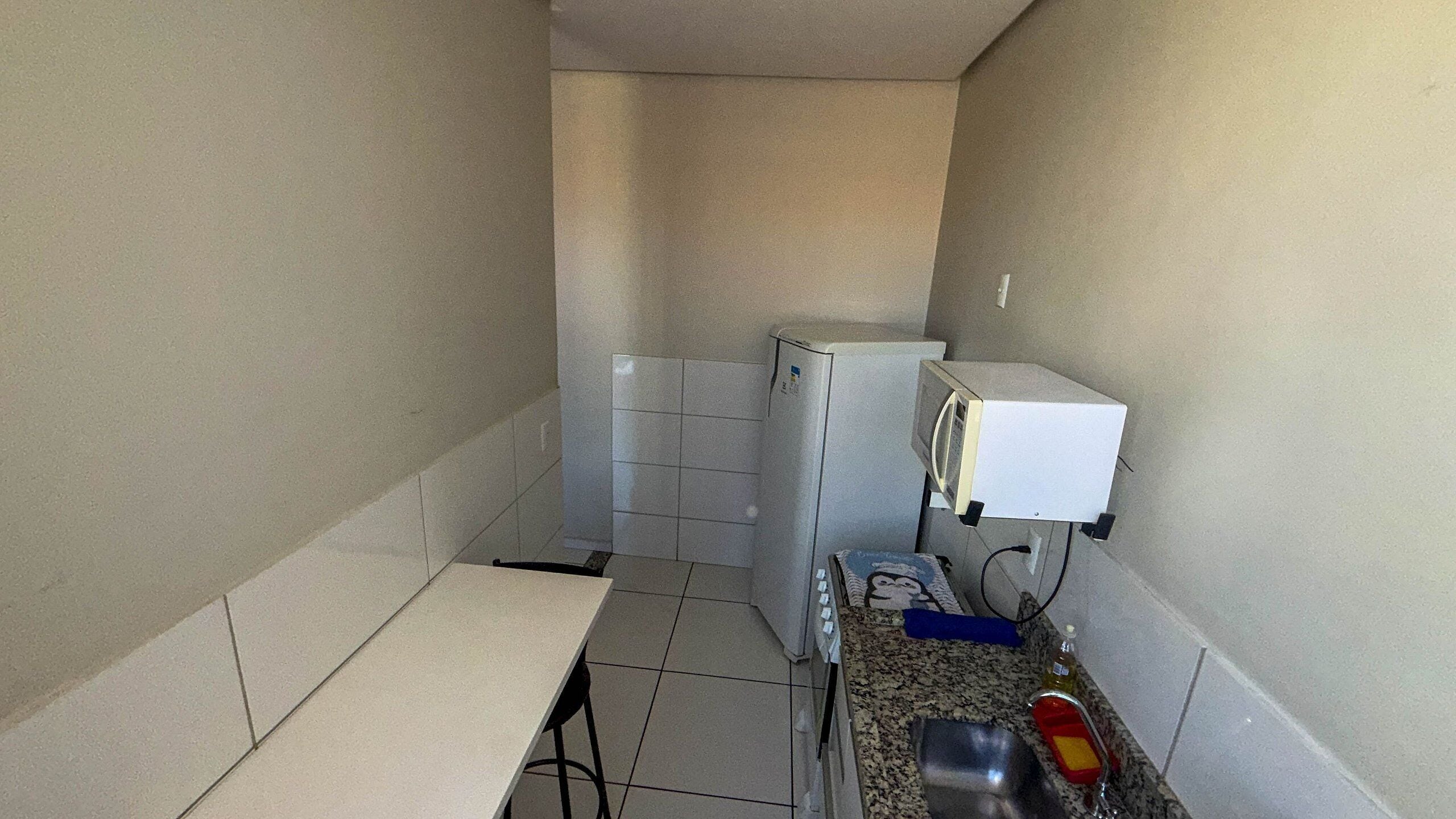 A small kitchenette with a refrigerator, microwave, and sink.