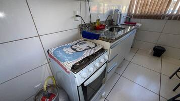 A kitchen with a gas stove, a sink, and a tiled backsplash.