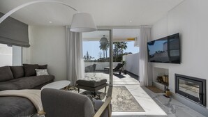 Una sala de estar moderna con un sofá gris, una mesita redonda y un televisor montado en la pared.