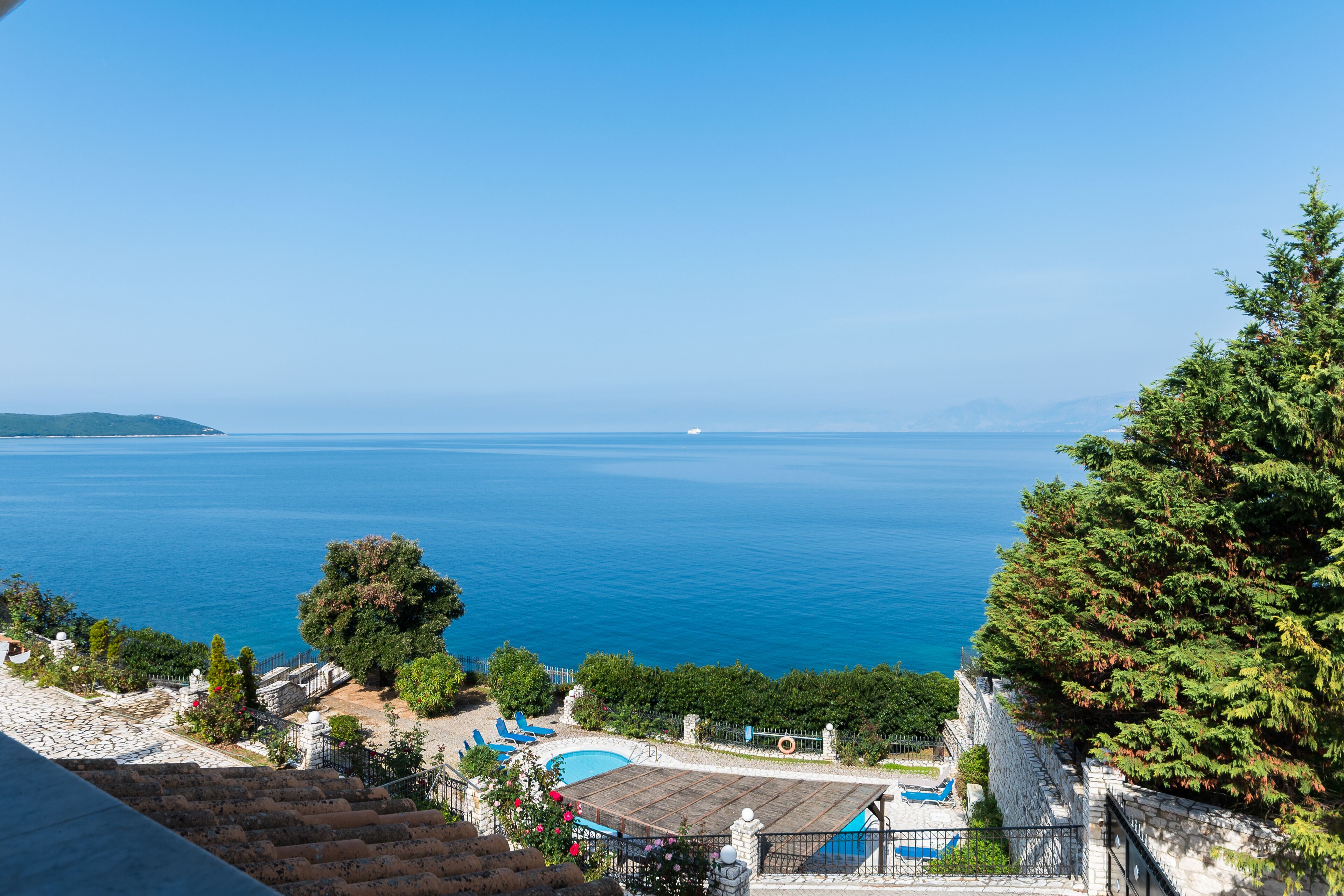 A coastal property with a swimming pool, a staircase leading to a terrace, and a view of the sea.