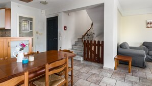 Una cocina moderna con armarios de madera, una mesa de comedor con sillas, una escalera con barandal de madera y un sofá gris en una sala de estar.
