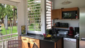 A compact kitchen with a built-in microwave, a coffee maker, and a sink. There's a window with blinds, a chair, and a small dining table. - Anse des Rochers lovely "1,2,3 Soleil" studio with superb sea view. (Saint Francois)