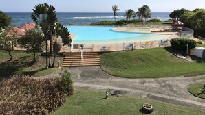 A pool with a view of the ocean, surrounded by palm trees and a gazebo. - Anse des Rochers lovely "1,2,3 Soleil" studio with superb sea view. (Saint Francois)
