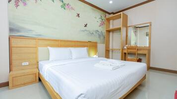 A neatly made bed with white linens, a wooden headboard, and a wall mural with floral and bird designs.