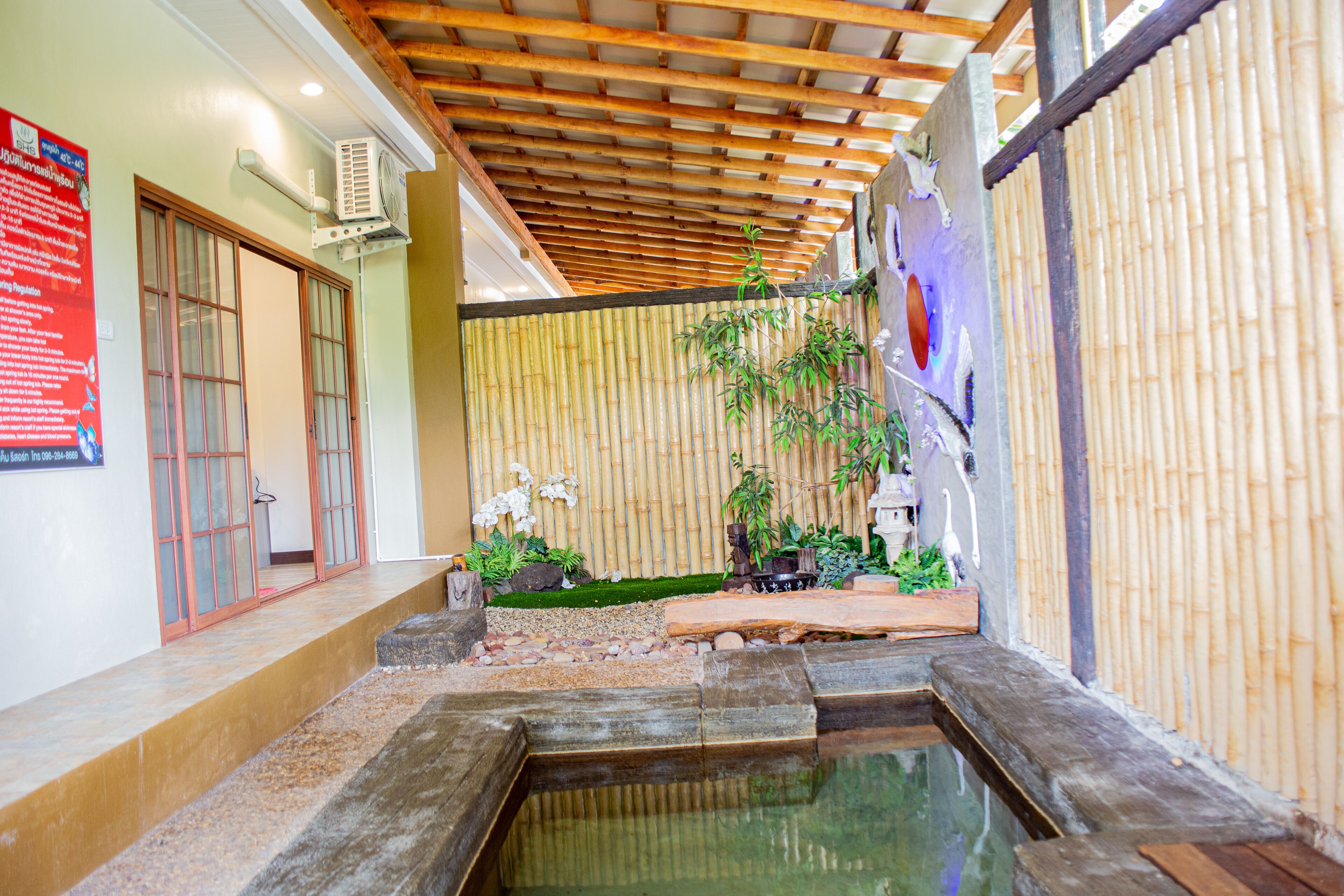 A traditional Japanese-style interior with a tatami mat floor, a small water feature, and a bamboo wall.