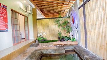 A traditional Japanese-style interior with a tatami mat floor, a small water feature, and a bamboo wall.