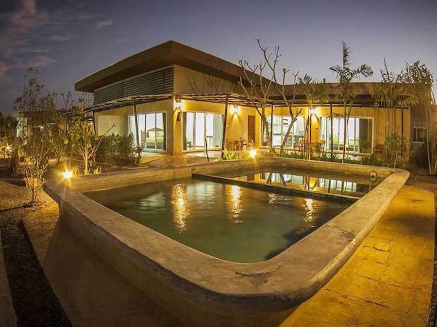 Una casa moderna con piscina, ventanas amplias e iluminación exterior.
