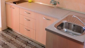 Une cuisine avec des meubles de couleur bois clair, un évier en acier inoxydable et un carrelage au motif décoratif.