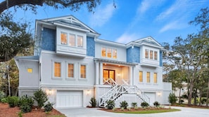 A two-story house with a front porch, a garage, and a staircase leading to the entrance.