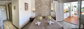 A hotel room with a bed, a stone wall, a small table, and a view of the outside balcony.