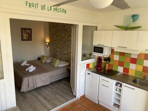 A compact room with a bed, a small kitchenette, and a bathroom.