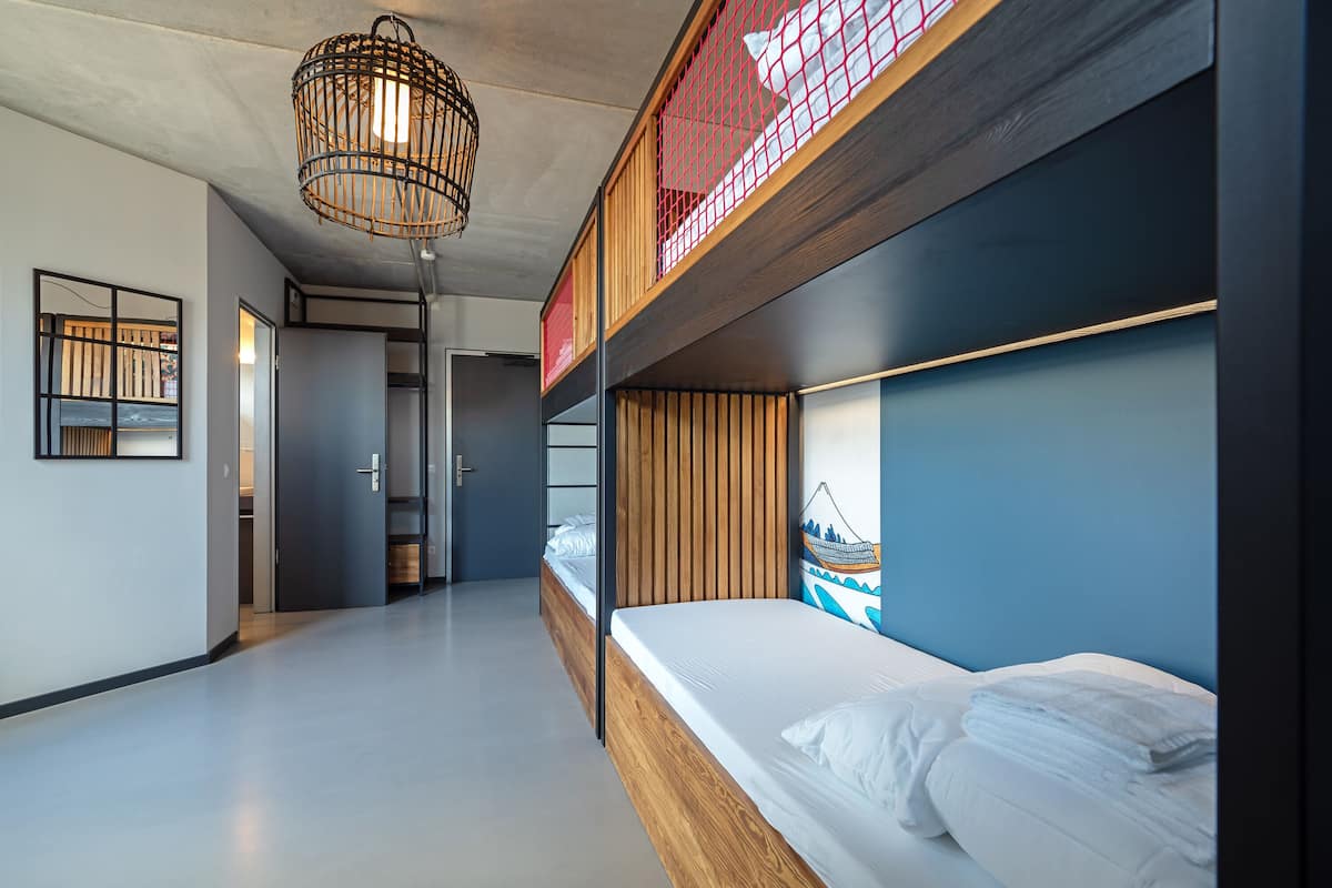 Ein modernes, mehrgeschossiges Schlafzimmer mit Etagenbetten, einem Holzkopfteil und einer Pendelleuchte.