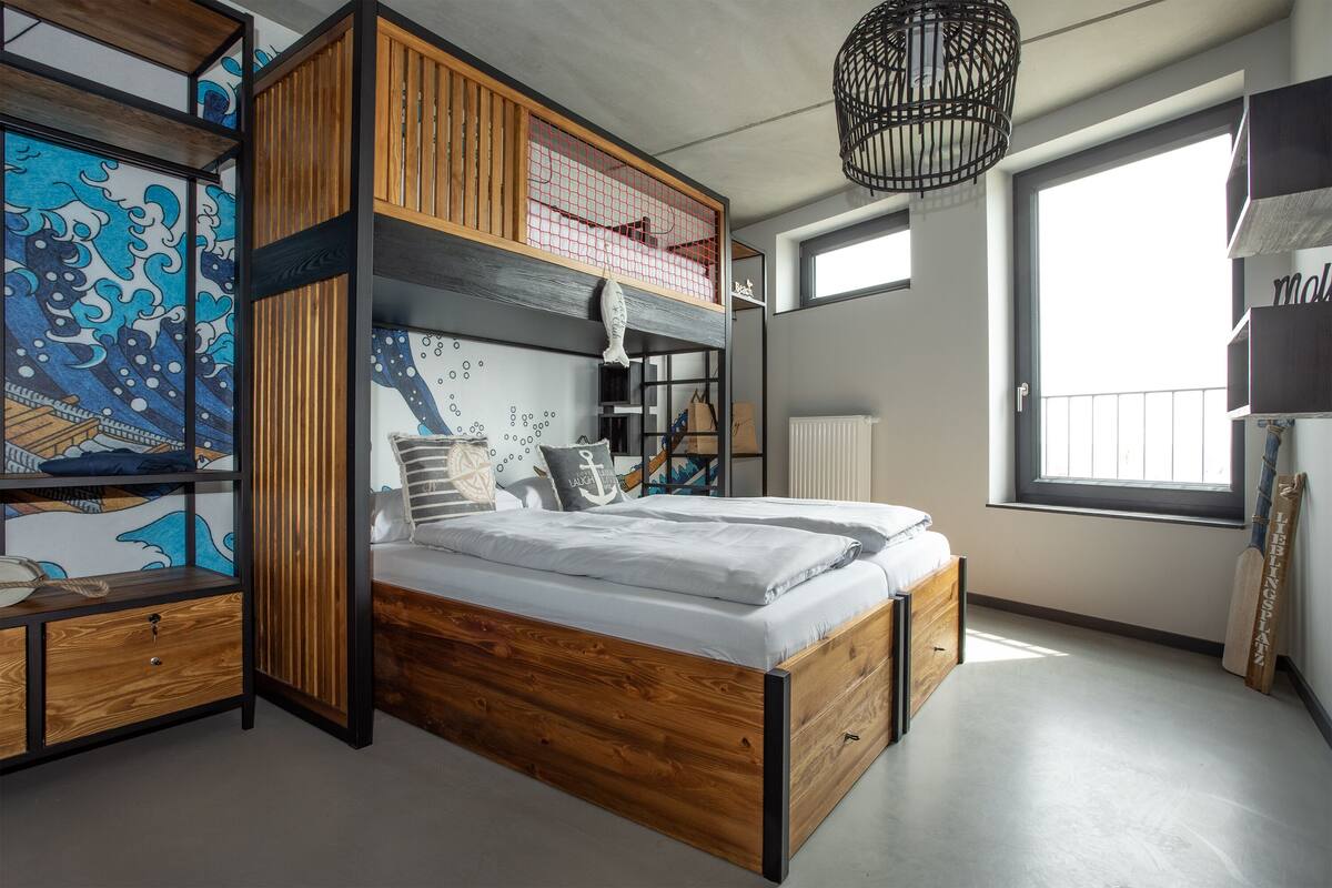 Ein modernes Schlafzimmer mit Etagenbett, Holzmöbeln und einem großen Fenster.