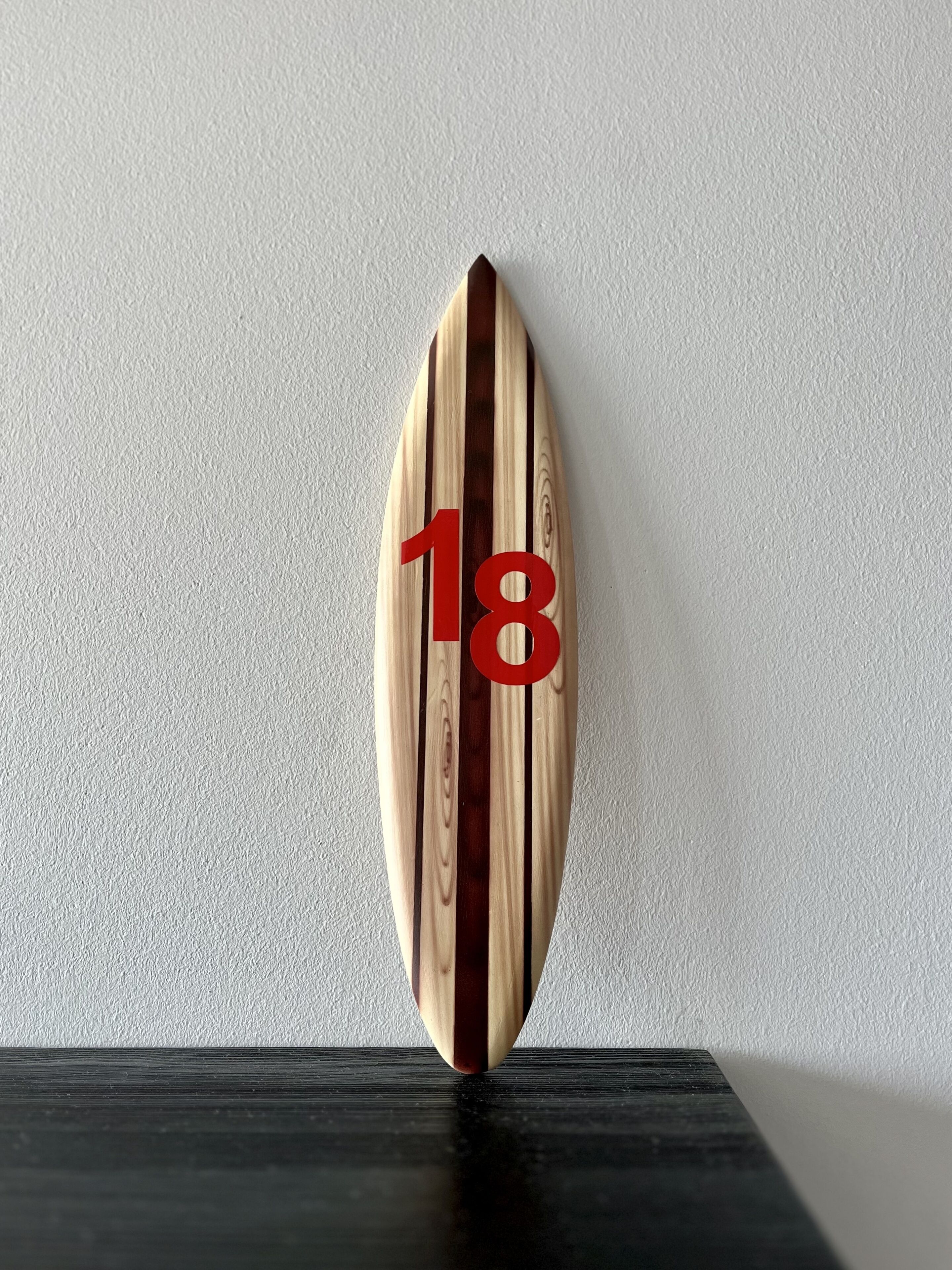 A wooden surfboard with the number 18 on it.