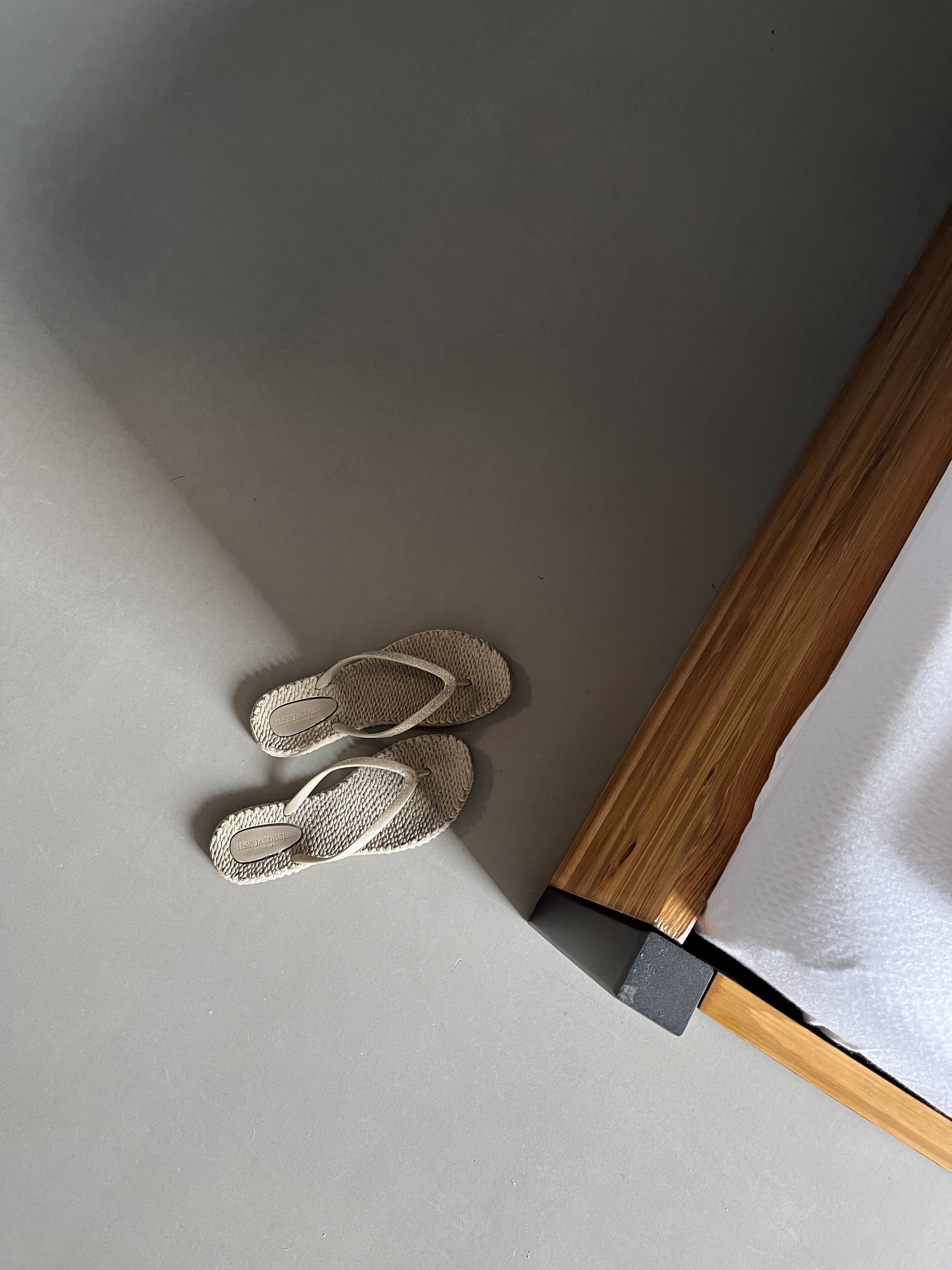 A pair of flip-flops on a grey surface next to a wooden frame.
