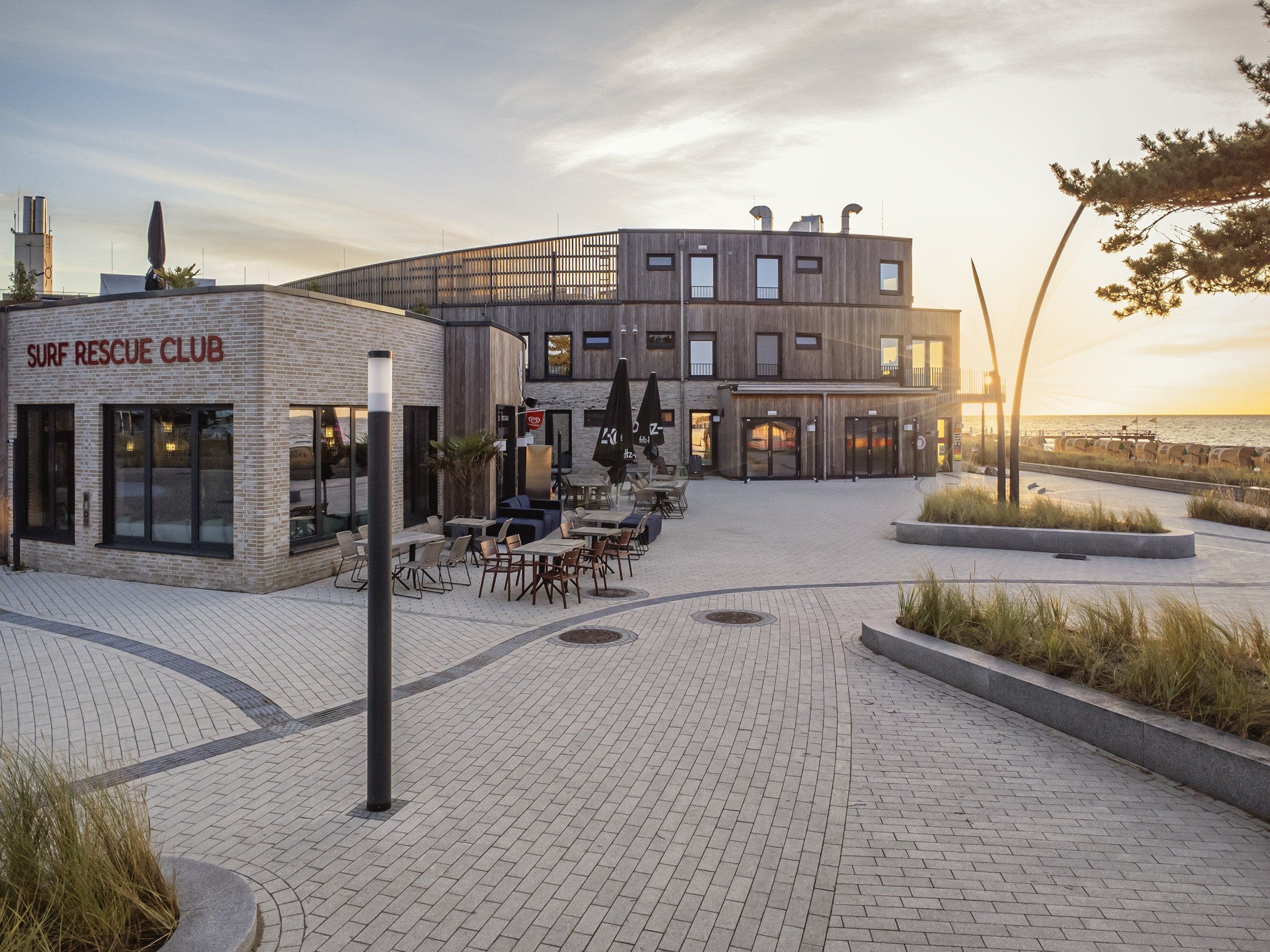 A building with a sign reading 'SURF RESCUE CLUB' and outdoor seating area with tables and chairs.