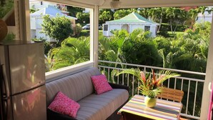 A balcony with a sofa, a small table, and a refrigerator. - Anse des rochers, very pretty "Bamboo" studio 30 meters from the beach. (Saint Francois)
