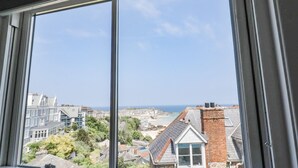 A window with a view of a coastal town, including buildings and a beach.