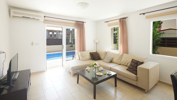 A modern living room with a sofa, coffee table, and a TV. - Protaras Holiday Villa Cl19 (Paralimni)