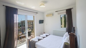 A hotel room with a bed, curtains, a window, a radiator, and a television. - Protaras Holiday Villa Cl19 (Paralimni)