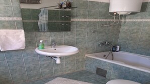 A bathroom with a sink, bathtub, toilet, and a mirror. - Apartment Marijana (Obrovac)