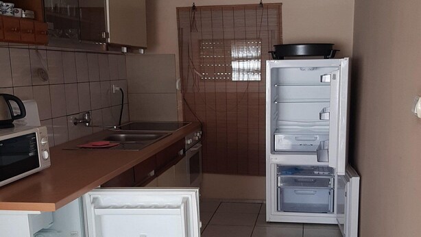 A compact kitchen with a refrigerator, microwave, and a small oven. - Apartment Marijana (Obrovac)