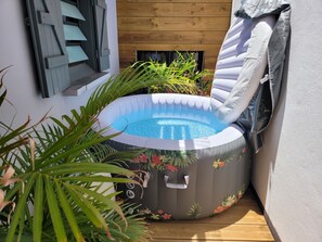 Ein aufblasbarer Pool mit floralem Muster, umgeben von Pflanzen und einer Holzverkleidung.