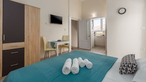 Una camera d'albergo con un letto, una scrivania, una sedia, un armadio e vista sulla cucina.