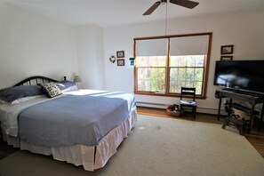 A bedroom with a bed, a ceiling fan, a window with blinds, a television, and a small table. - Sprawling Home With Private Association Lake Access (2289) (Orleans)