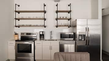 A modern kitchen with stainless steel appliances, wooden shelves, and a neutral color palette.