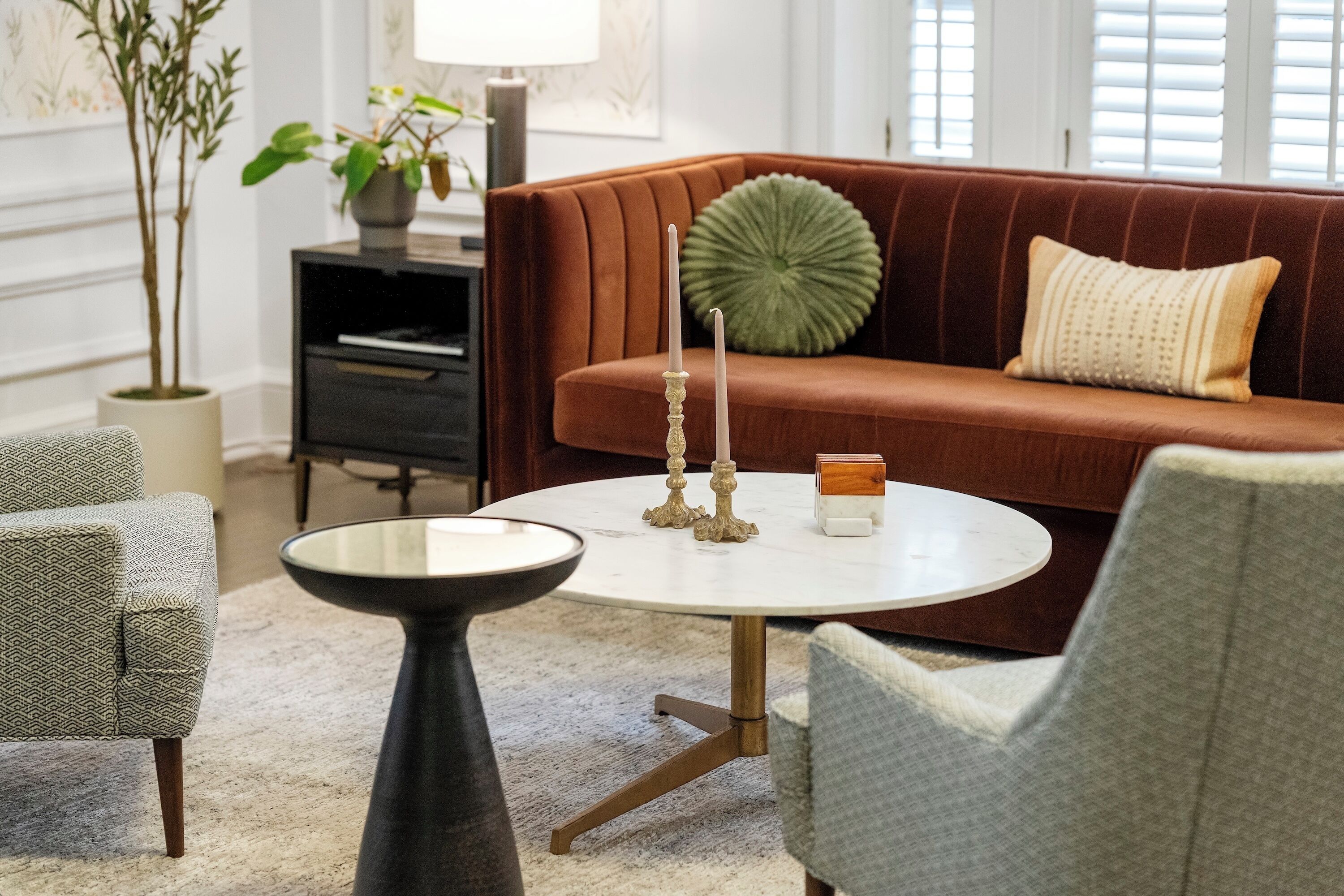 A living room with a brown sofa, a round coffee table, and a grey armchair.