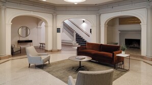 A spacious lobby with a grand staircase, a fireplace, and a modern seating area. - Kasa Capitol Hill Downtown Nashville (Nashville)