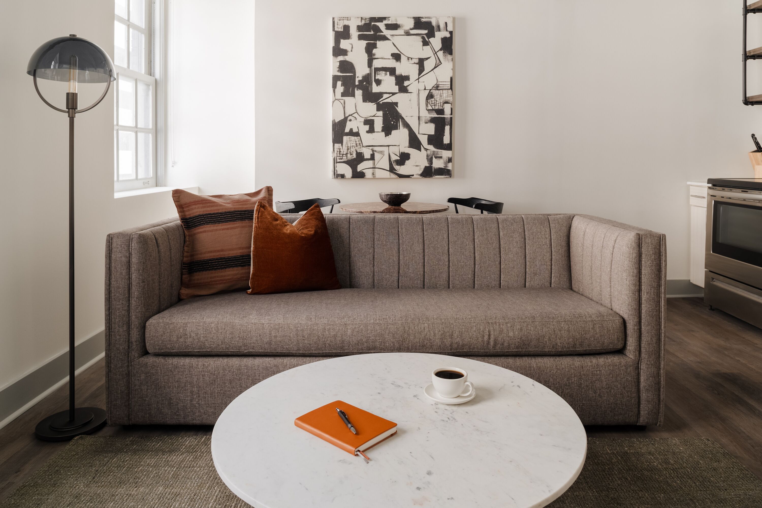 A modern living room with a grey sofa, a round coffee table, and a floor lamp.