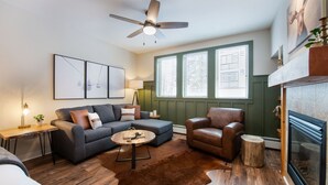 A living room with a sofa, armchair, coffee table, and fireplace. - Premium Unit 3318 - Studio - Fraser Crossing/founders Pointe Condo (Winter Park)