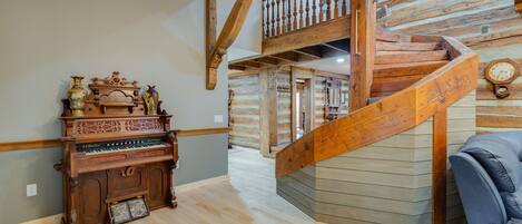 A wooden staircase with a railing, a piano, and a clock on the wall.