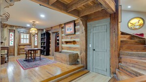 Ein rustikales Interieur mit Holzwänden, einer Treppe, einer Essecke mit Tisch und Stühlen sowie einem Bücherregal.