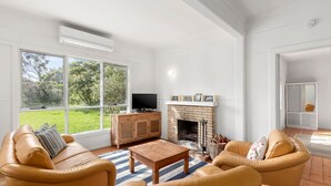 Amplia sala de estar con chimenea, sofás de cuero, una mesa de centro de madera y una televisión.