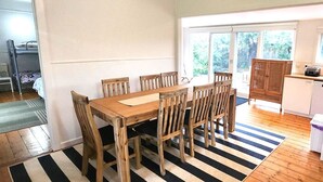 Un comedor con una mesa y sillas de madera, un tapete a rayas blancas y negras, y vistas del exterior a través de un ventanal.