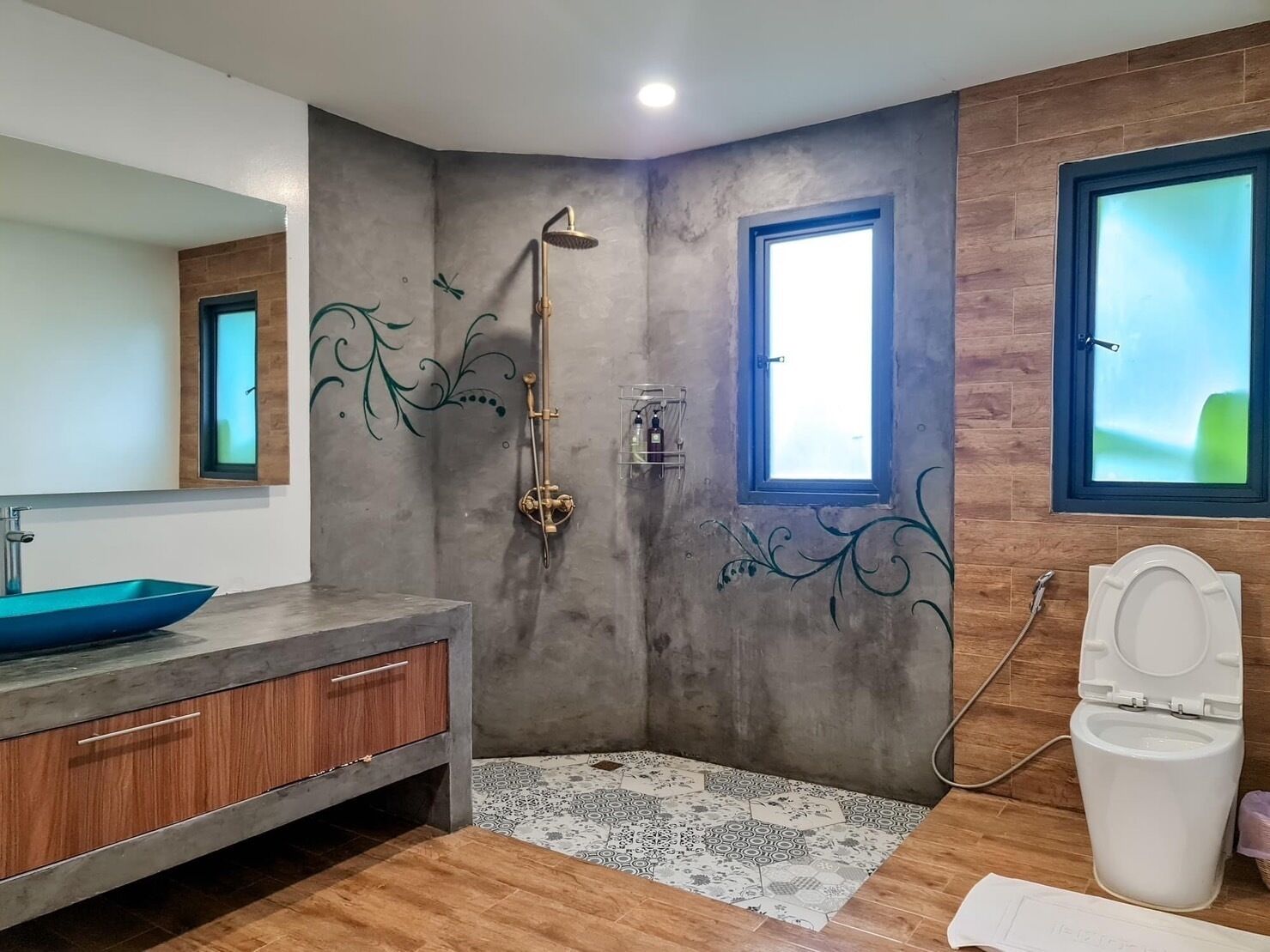 A bathroom with a modern design, featuring a large mirror, a vessel sink, a shower with a handheld showerhead, and a toilet.