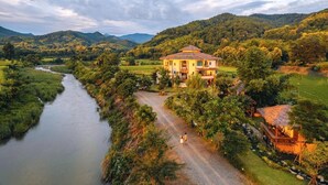 Una casa grande con un patio central, rodeada de abundante vegetación y un río.