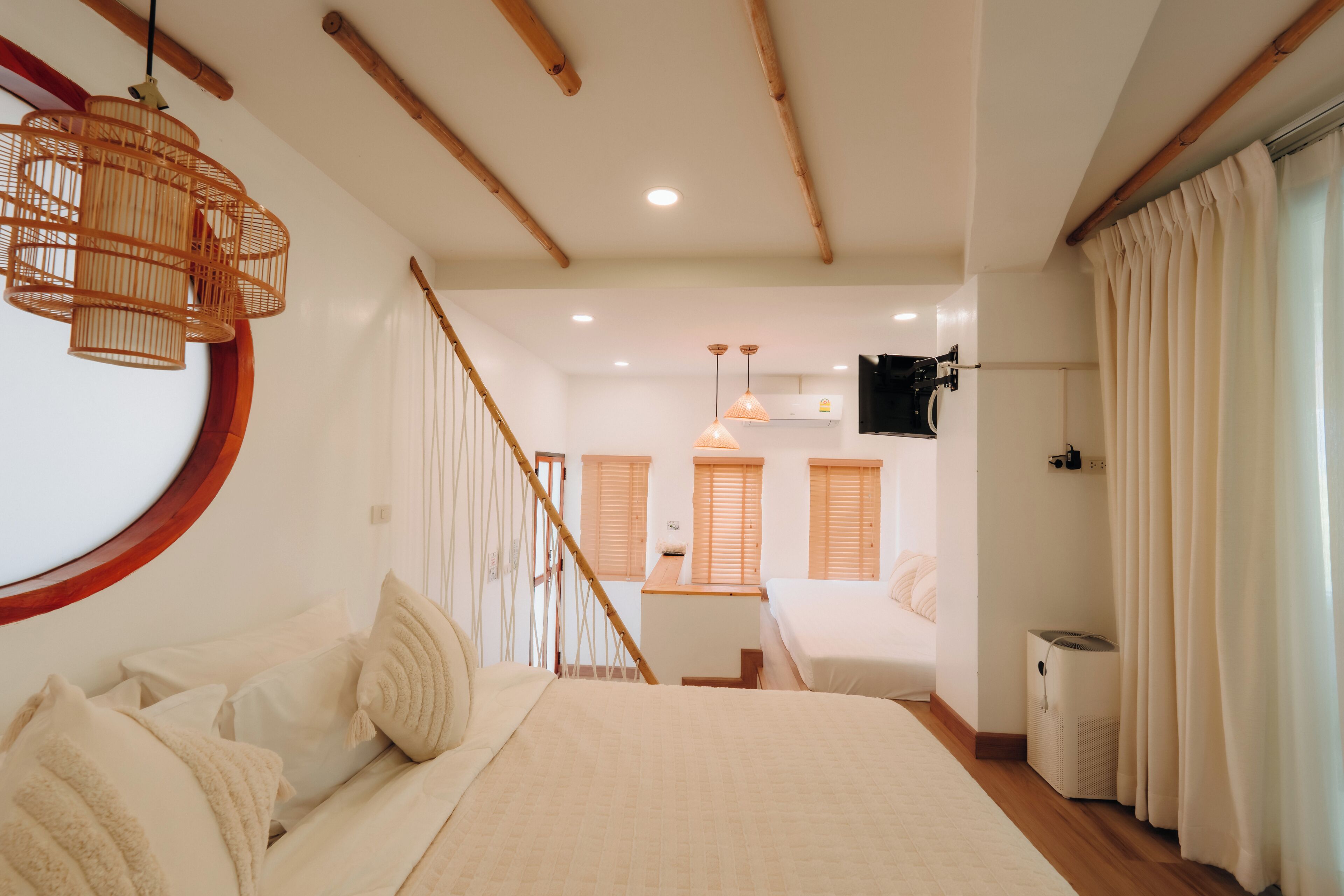 Un dormitorio con una cama, una escalera de madera, un ventilador de techo y un televisor montado en la pared.