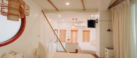 Un dormitorio con una cama, una escalera de madera, un ventilador de techo y un televisor montado en la pared.