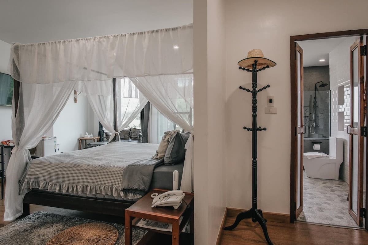 A bedroom with a bed, bedside table, and a floor lamp.