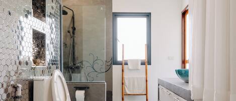 A modern bathroom with a toilet, shower, and sink.
