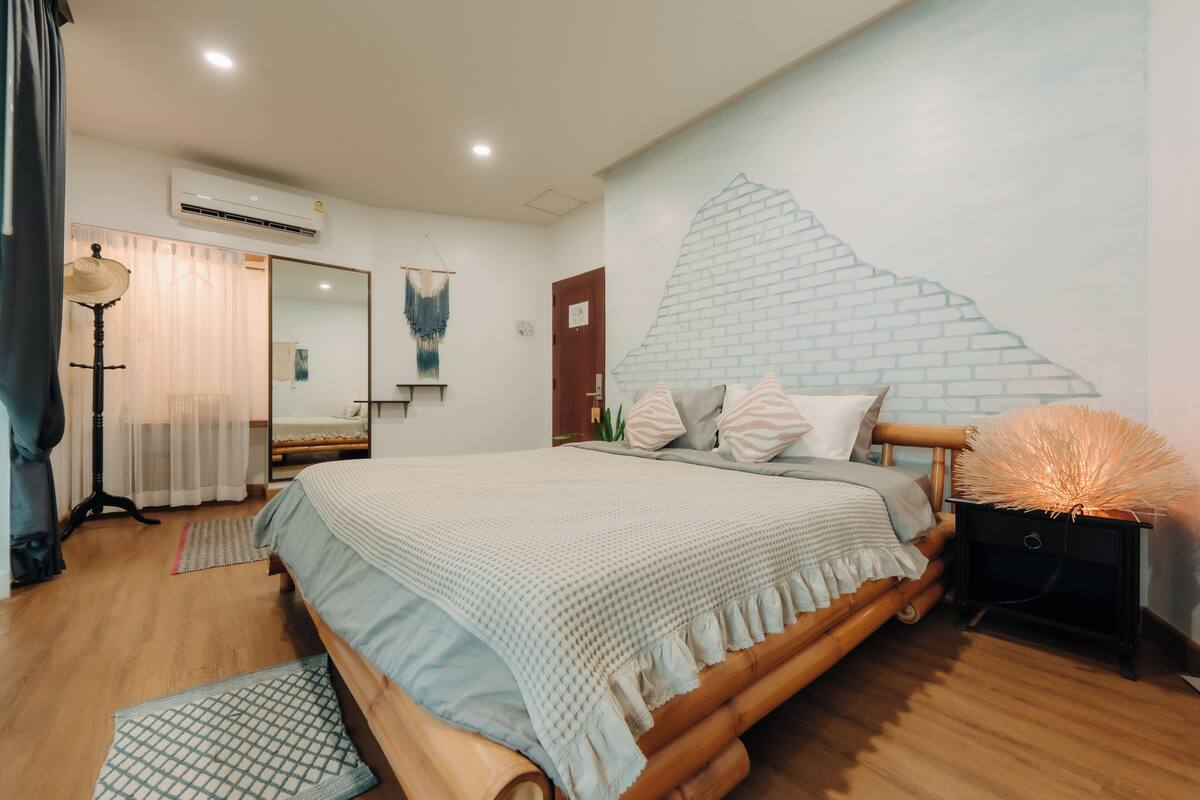 A bedroom with a bed, bedside table, lamp, and a wall mural.