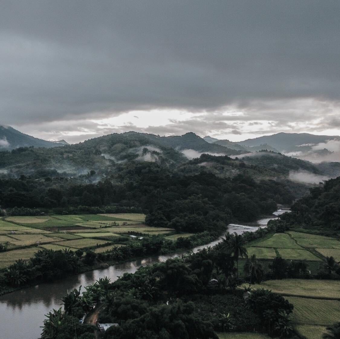 A rural landscape with terraced fields, a river, and rolling hills.