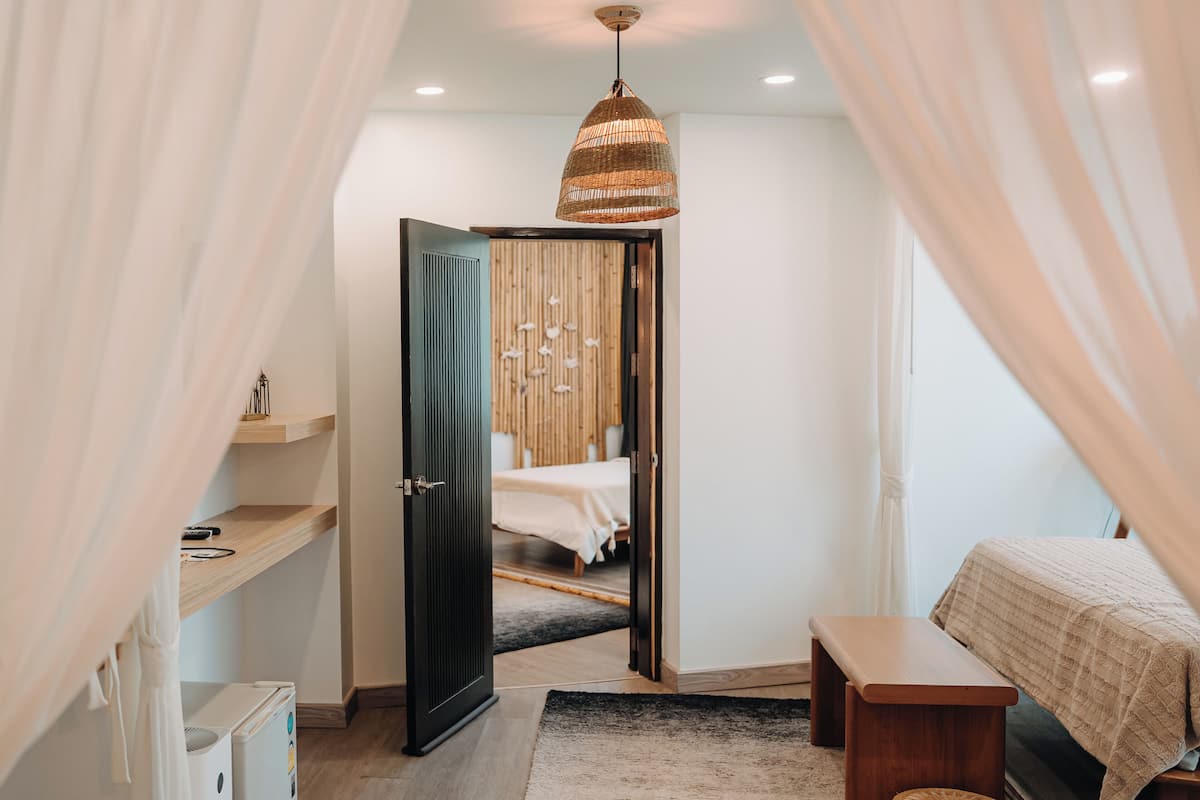A bedroom with a bed, bedside table, and a hanging light fixture.