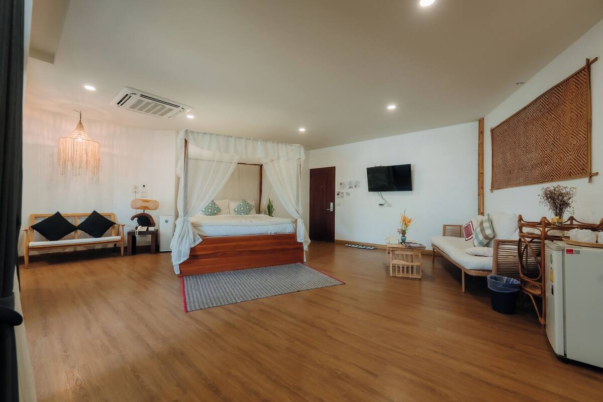 A room with a bed, a sofa, a TV, and a refrigerator.
