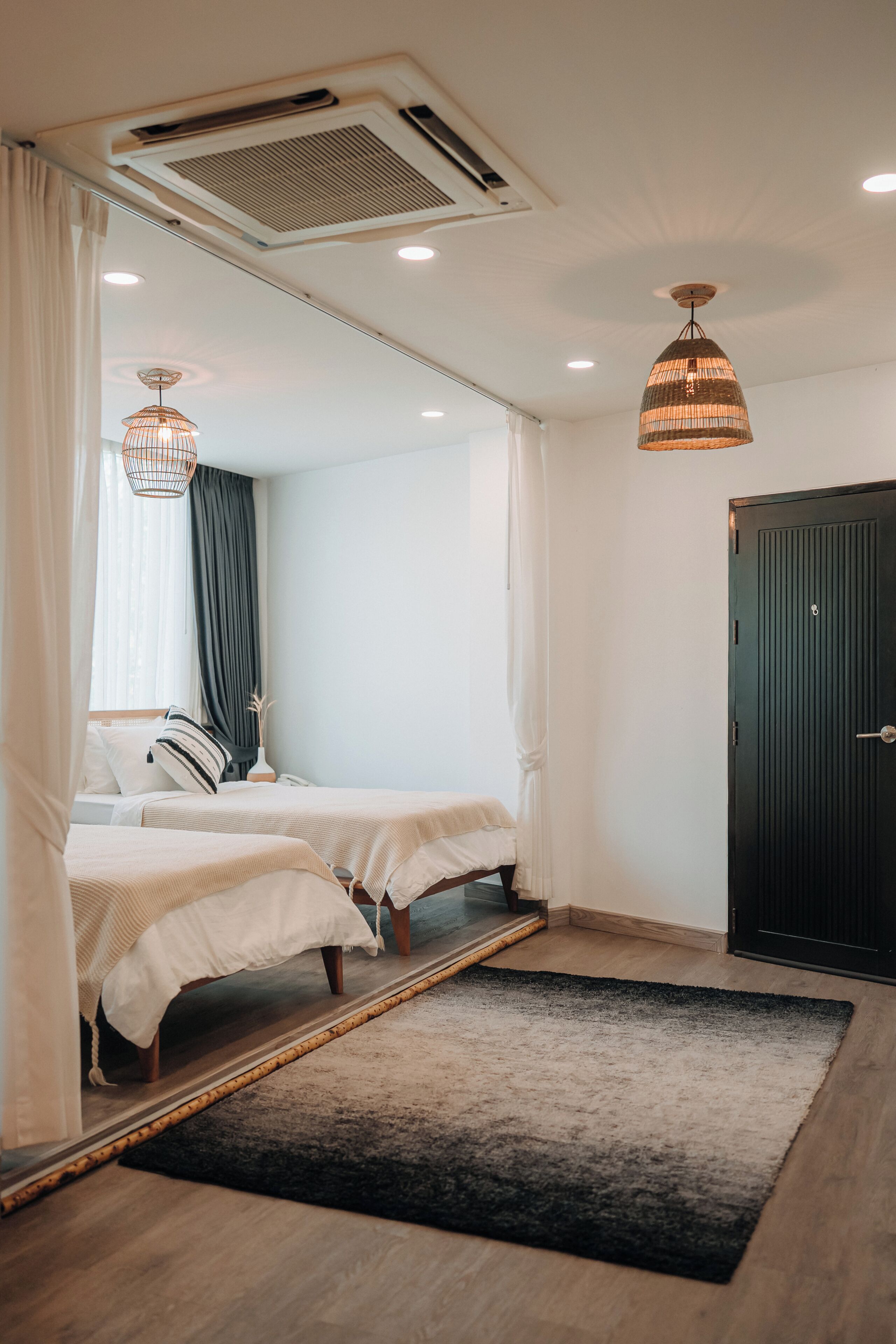 A bedroom with two beds, a black door, and a ceiling vent.