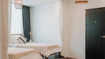 A bedroom with two beds, a black door, and a ceiling vent.